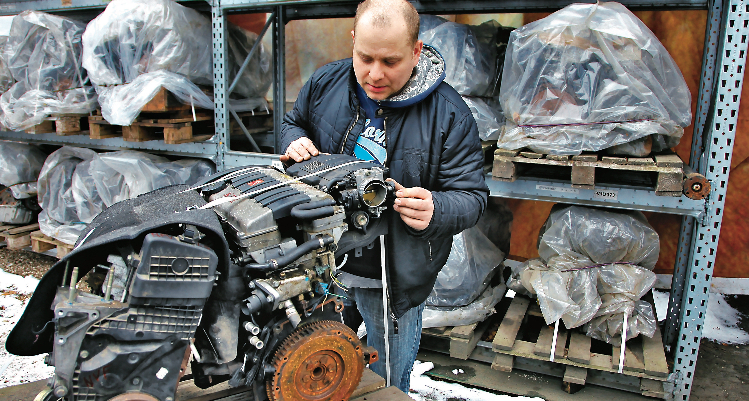 człowiek oglada uzywany silnik na szrocie