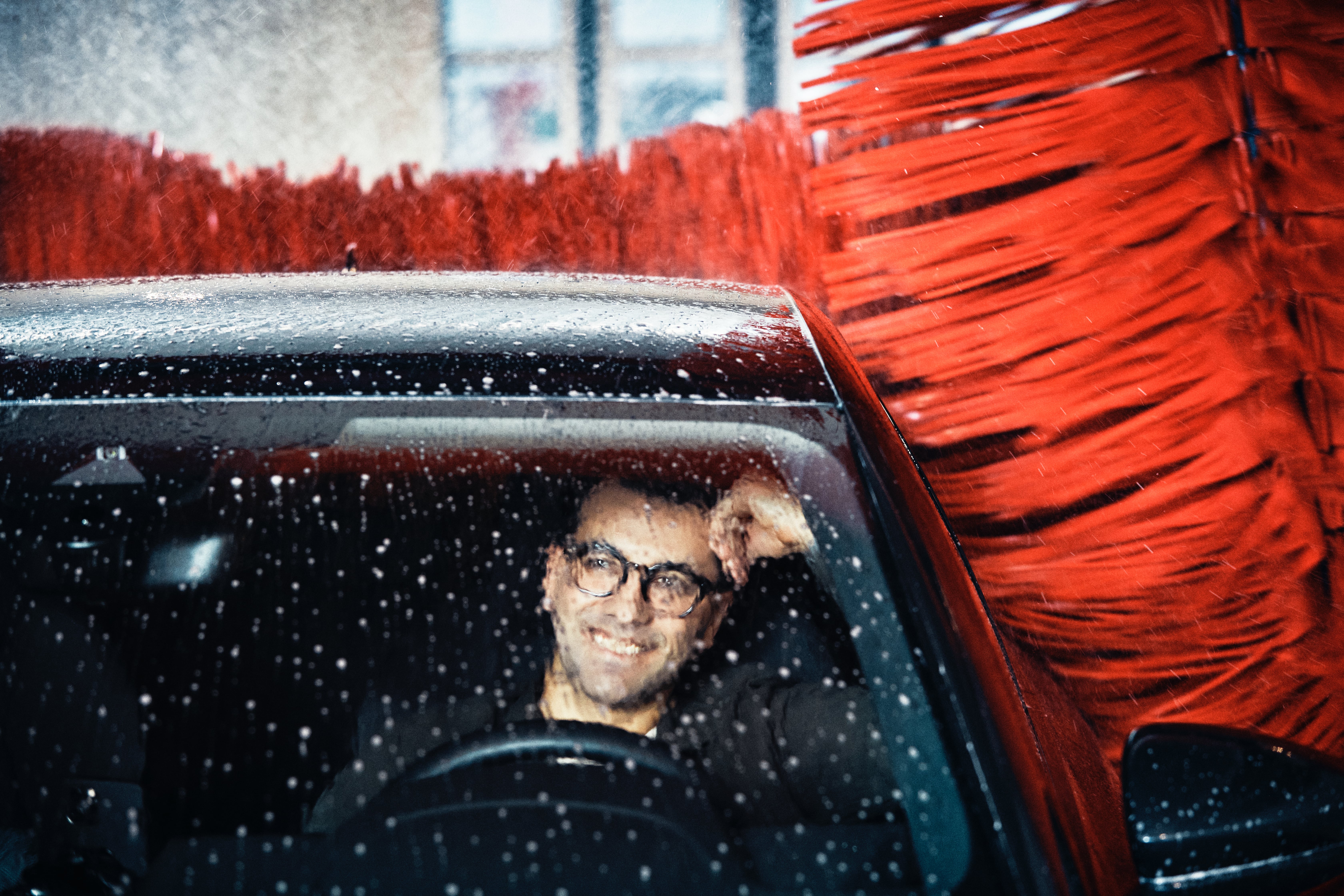 mężczyzna w aucie podczas mycia samochodu w myjni