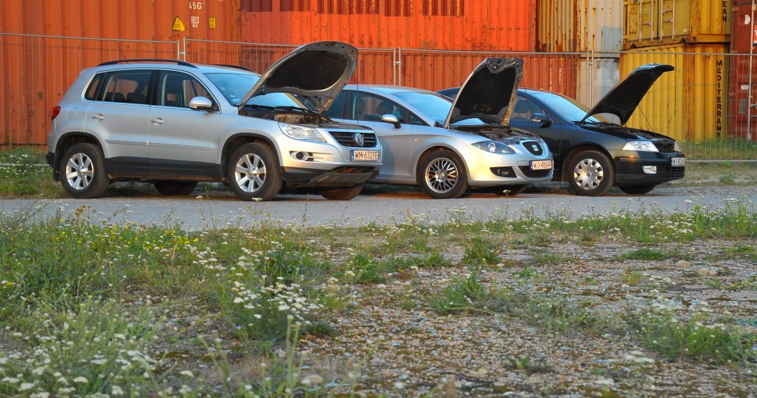 trzy auta z podniesionymi maskami