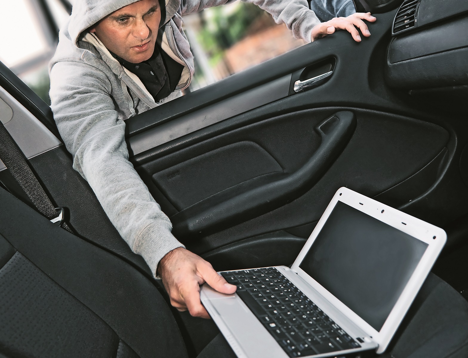 złodziej kradnie laptop z wnętrza auta