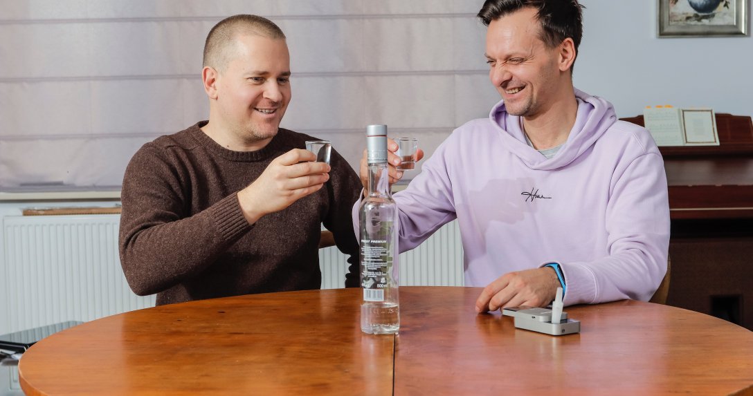 dwóch mężczyzn pije wódkę przy stole w mieszkaniu