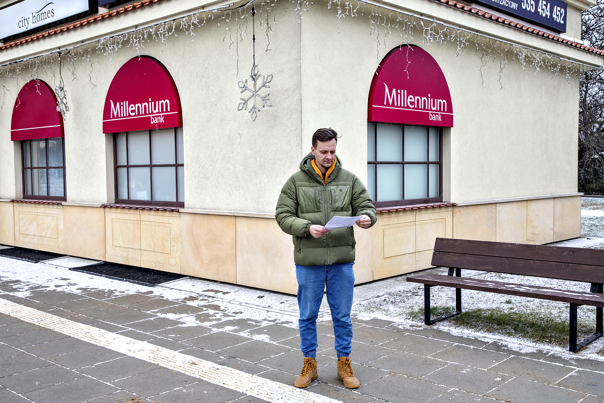 mężczyzna pod bankiem czyta umowę