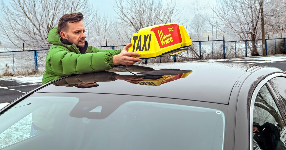 Taksówkarz mocuje znak taxi na dachu