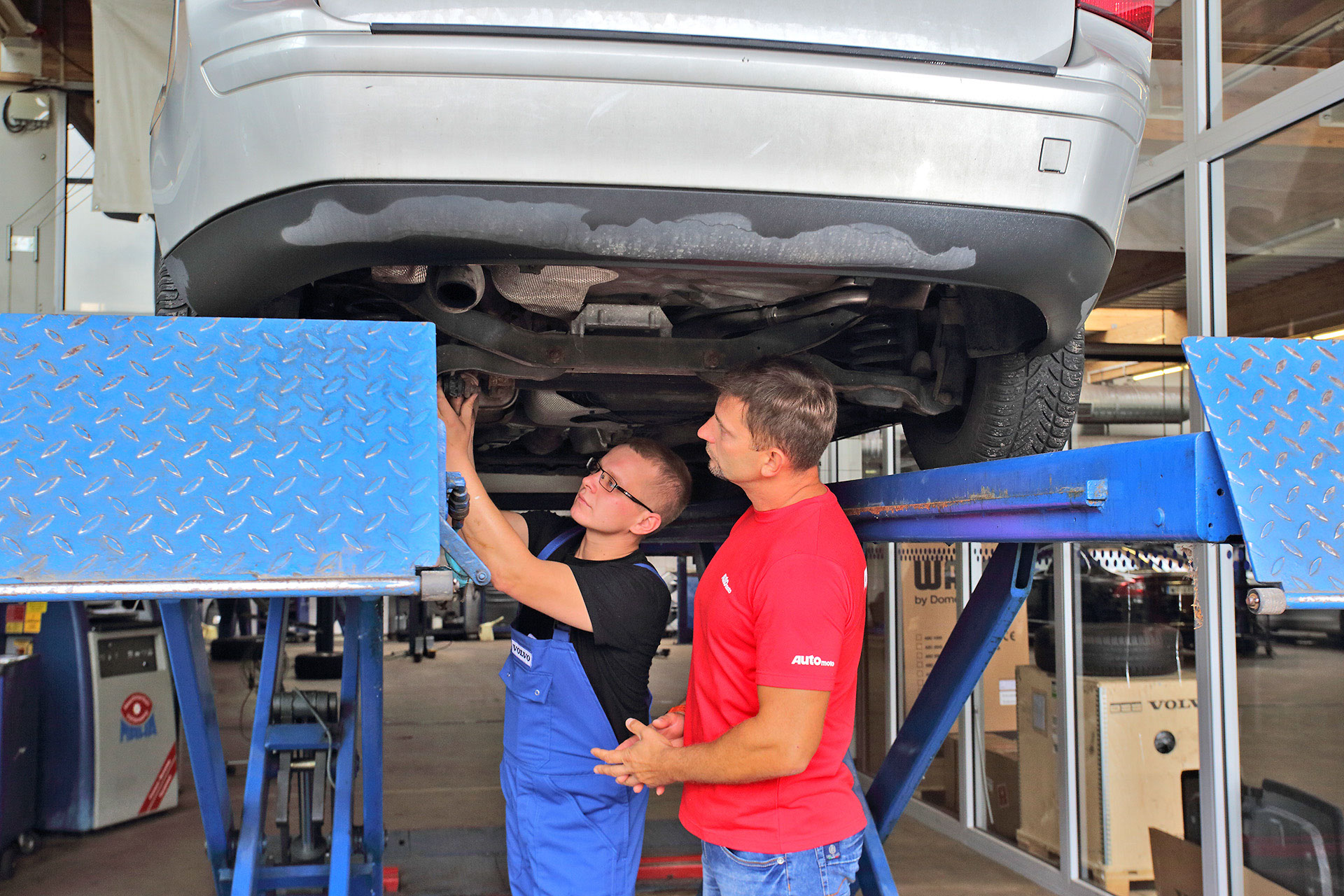 dwóch mężczyzn ogląda podwozie auta na podnośniku