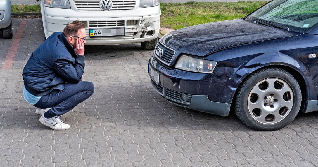mężczyzna ogląda przód Audi po kolizji, w tle – Mercedes z Ukrainy