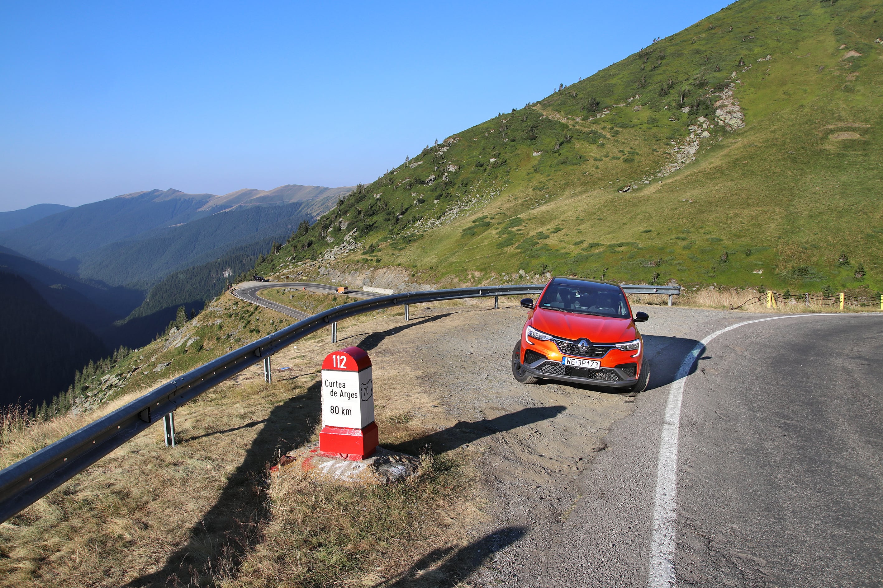 Renault Arkana E-Tech 145 przód na poboczu z serpentyną w tle