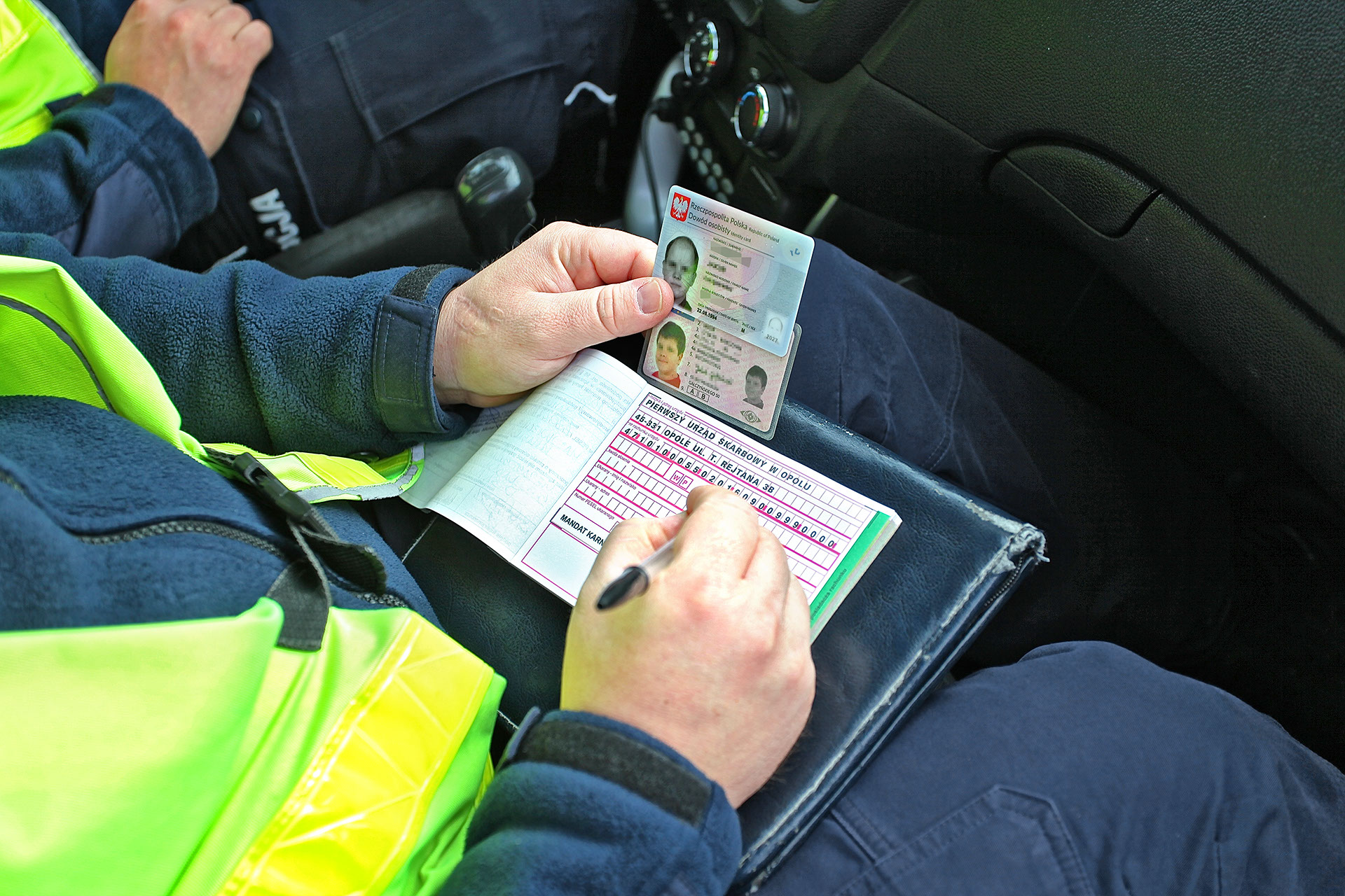 policjant wypisujący mandat na podstawie danych z dowodu osobistego i prawa jazdy