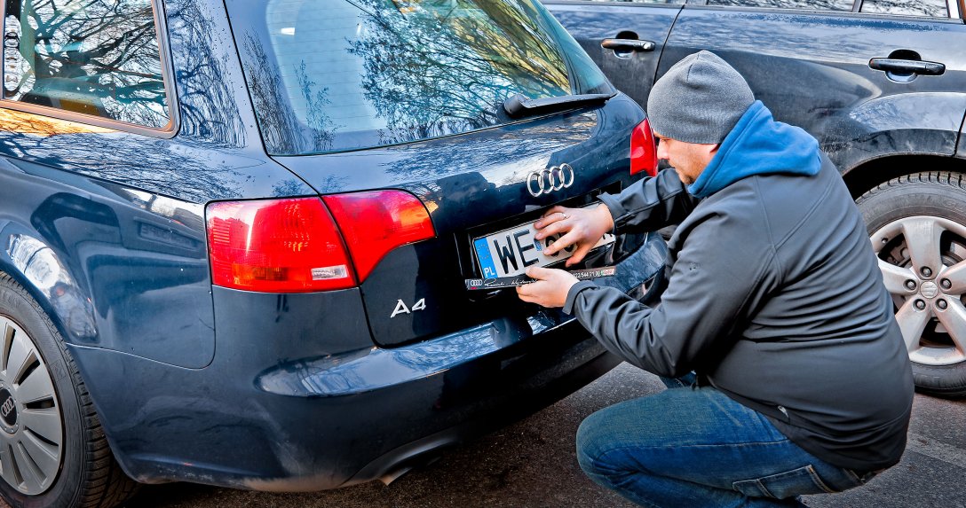 mężczyzna przymocowuje tylną tablicę rejestracyjną do Audi A4