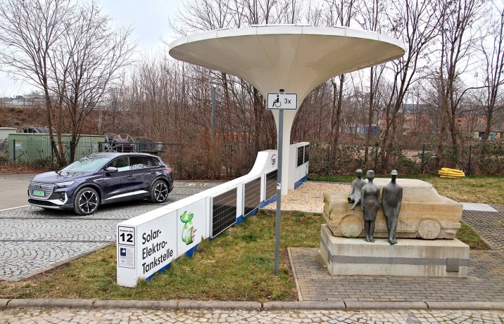 Audi Q4 e-tron obok stacji ładowania i pomnika Trabanta