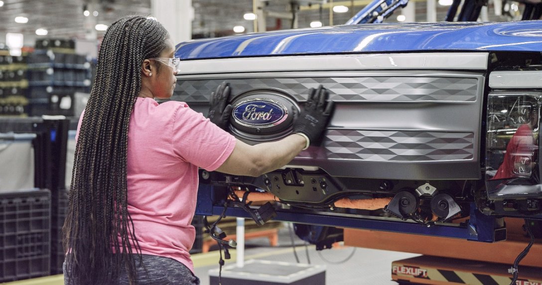 fabryka Forda – kobieta mocująca grill z logo Forda