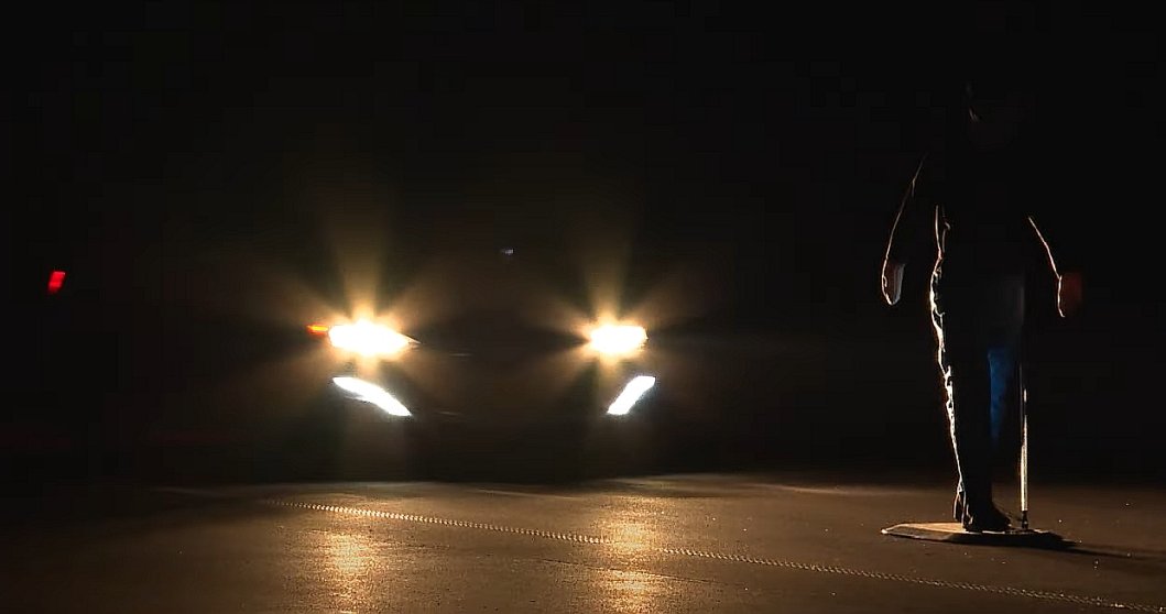 pieszy stojący w nocy naprzeciw samochodu