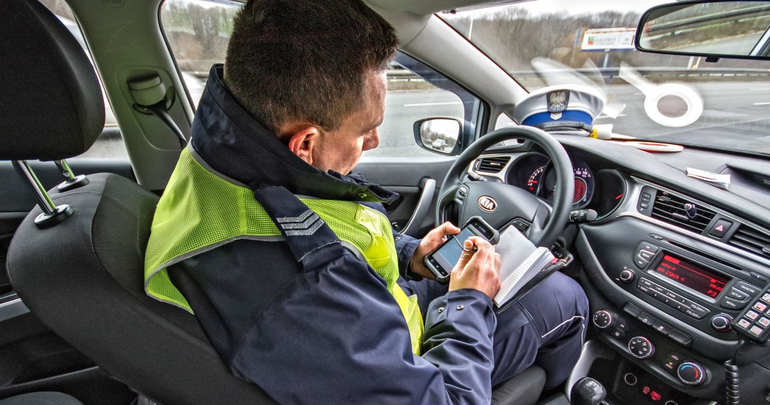 policjant w radiowozie sprawdza dokumenty kierowcy