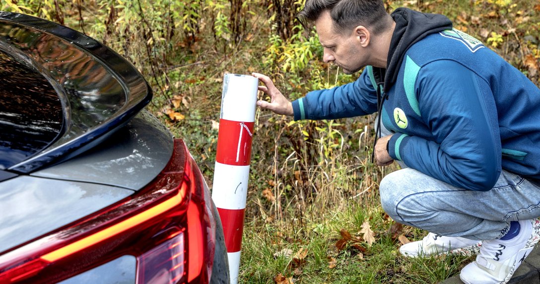 Kierowca ogląda uszkodzony słupek przy drodze