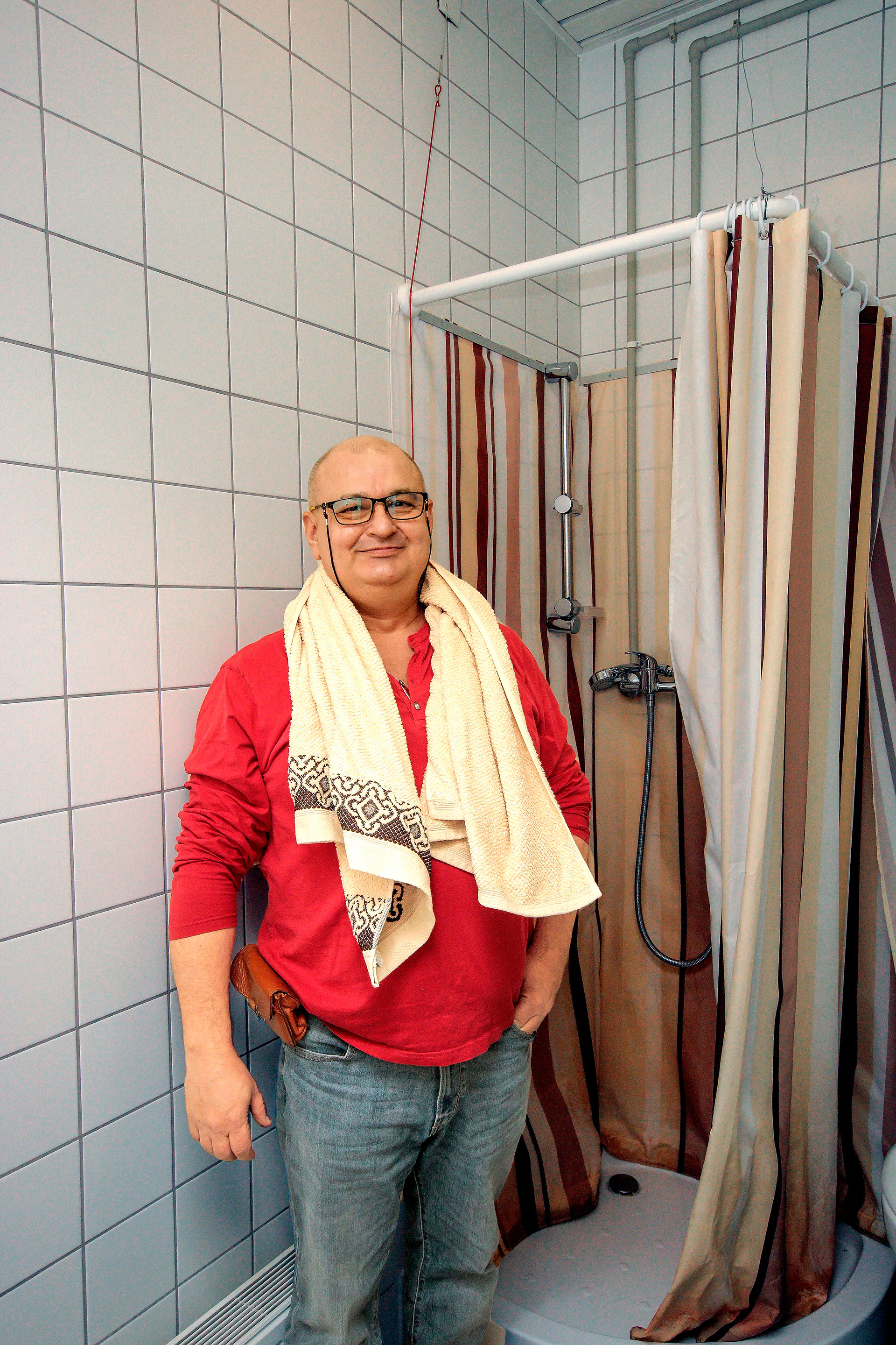 mezczyzna z recznikiem idzie pod prysznic