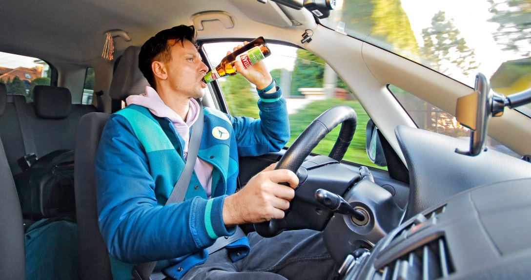 kierowca pije alkohol podczas jazdy samochodem