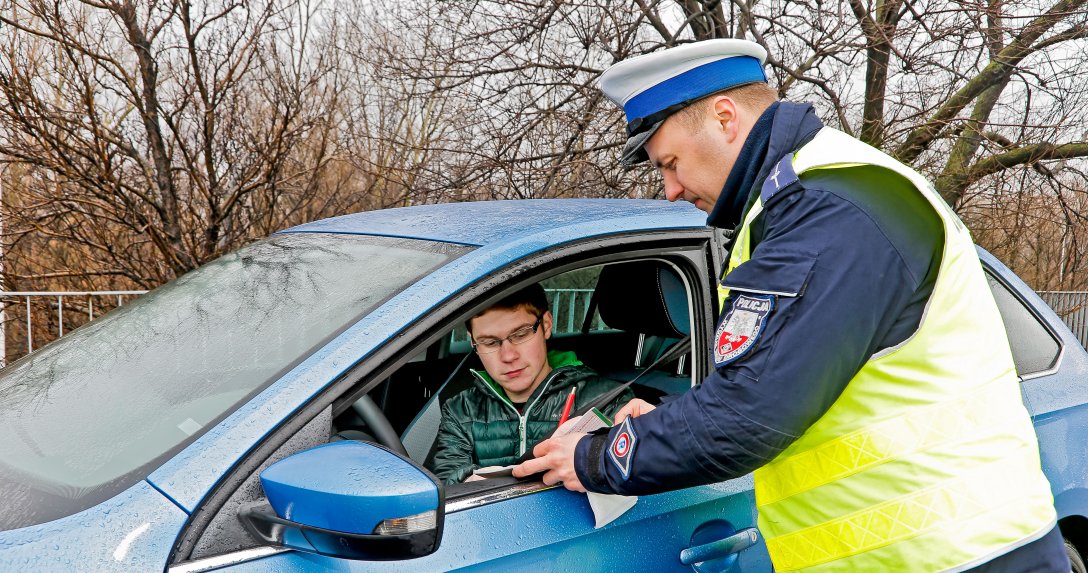policjant wręcza kierowcy mandat