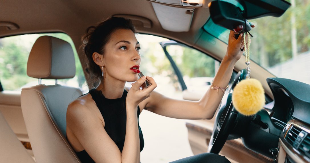 kobieta z kierownicą maluje usta