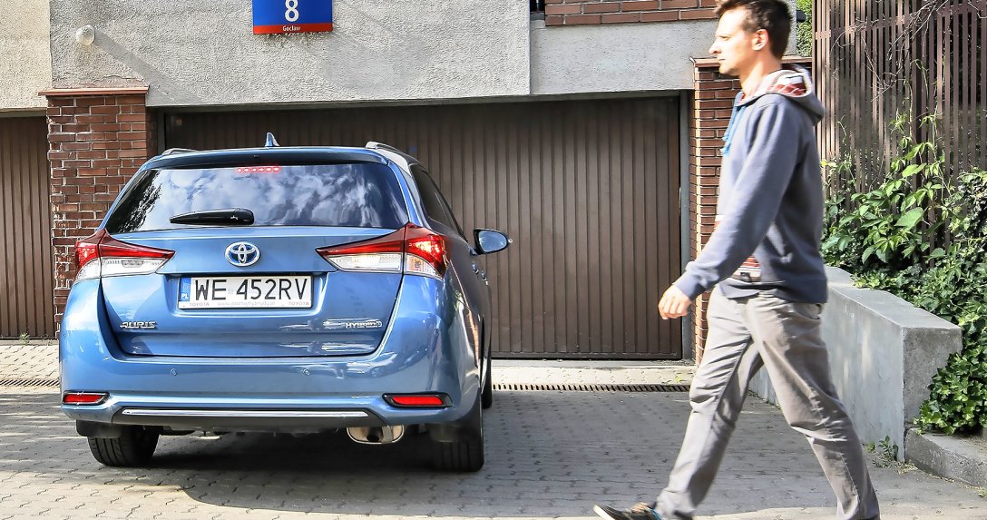 pieszy przechodzący za hybrydową Toyotą