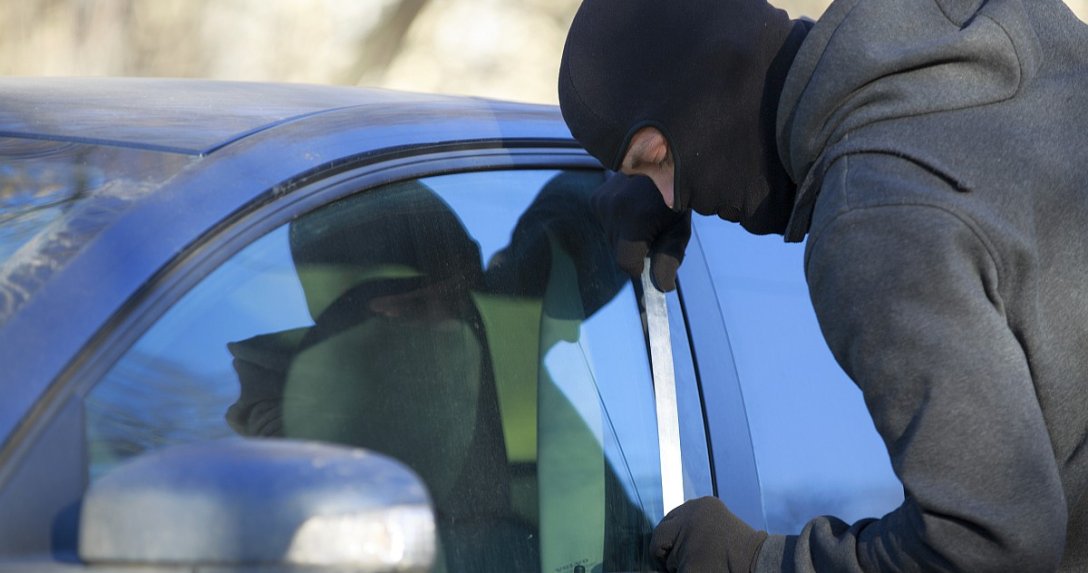 zamaskowany złodziej kradnie auto