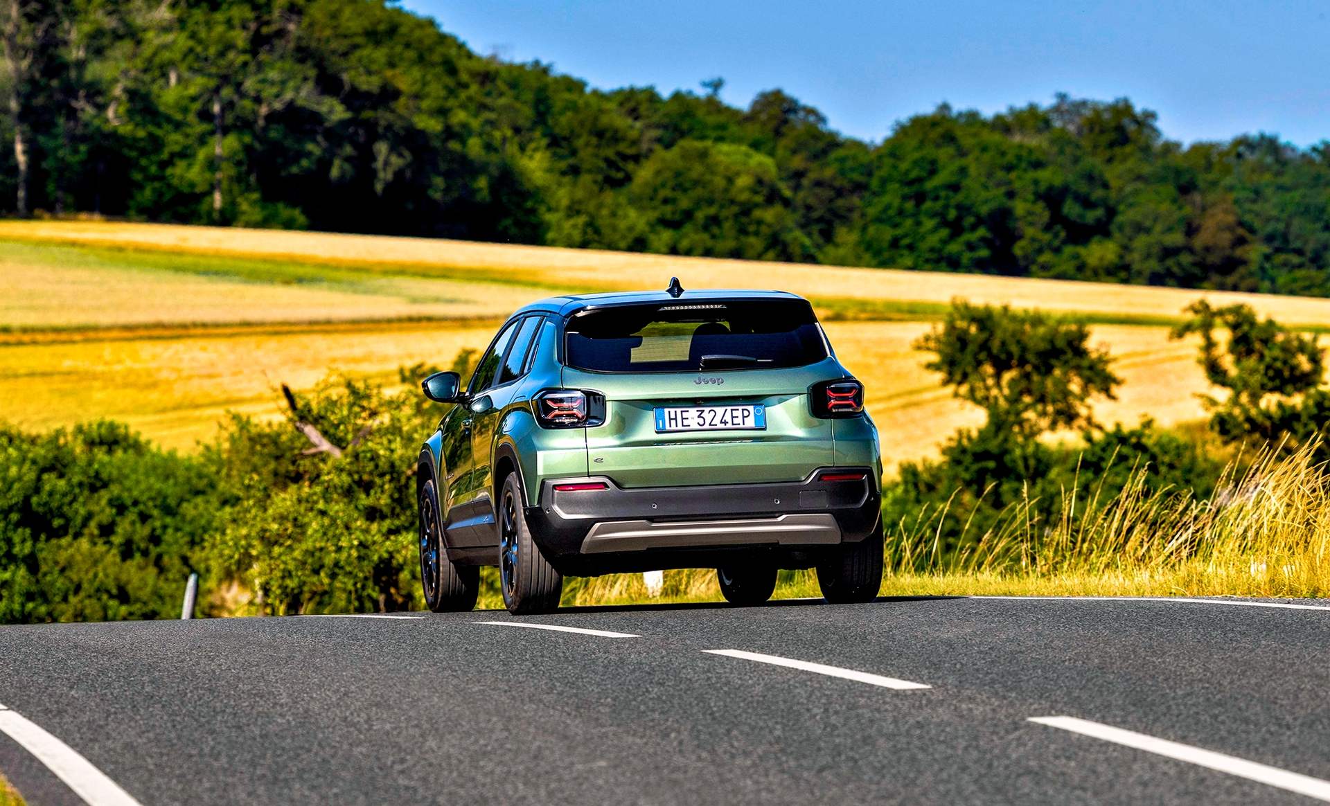 Jeep Avenger w kolorze Forest podczas jazdy, ujęcie z tyłu i boku.