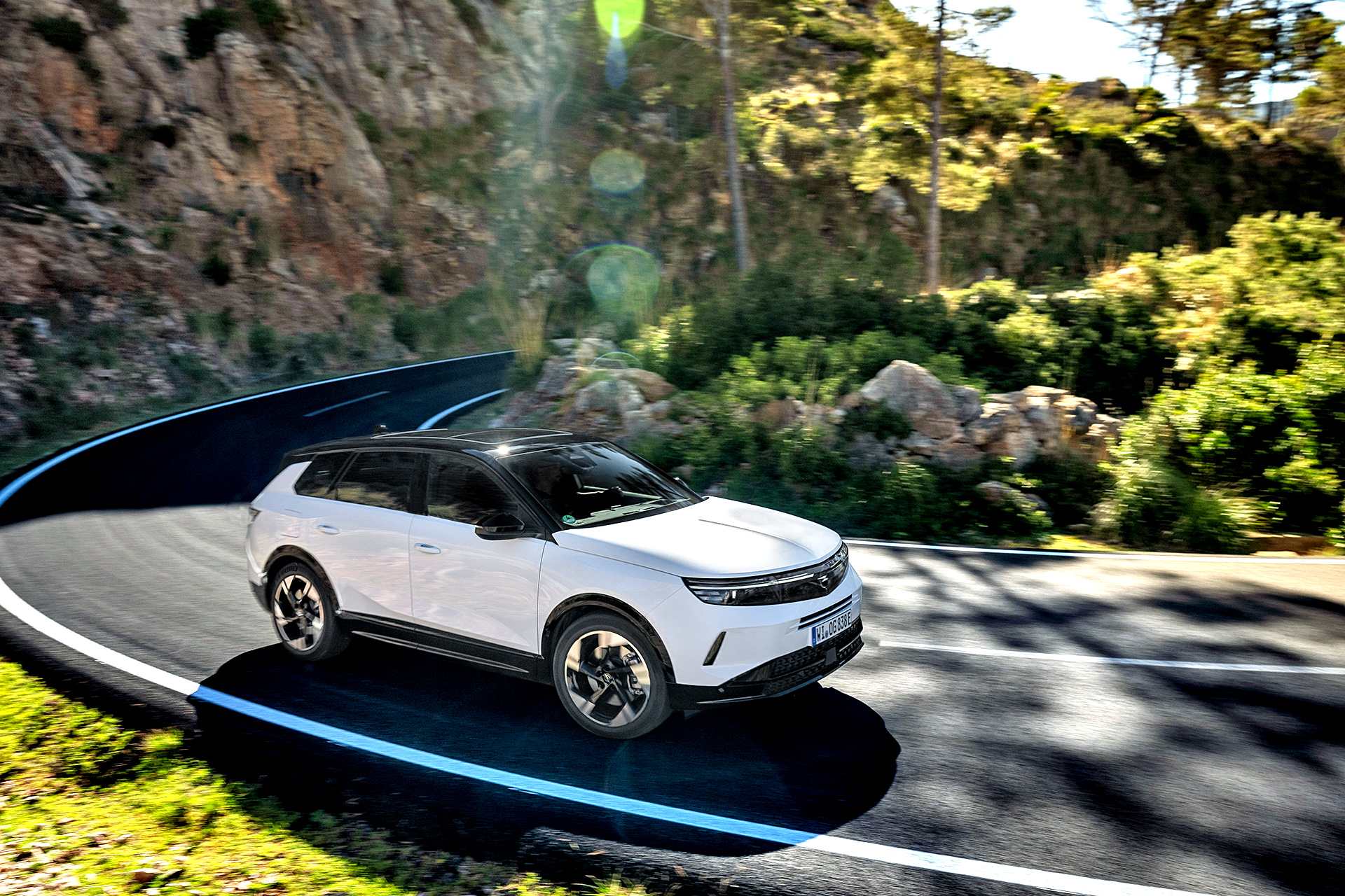 Opel Grandland Plug-in Hybrid w białym lakierze podczas jazdy, ujęcie z przodu i boku.