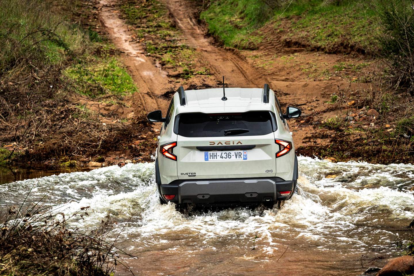 Biała Dacia Duster III hybrid-G 150 4x4 Extreme podczas przeprawy przez wodę, widok z tyłu